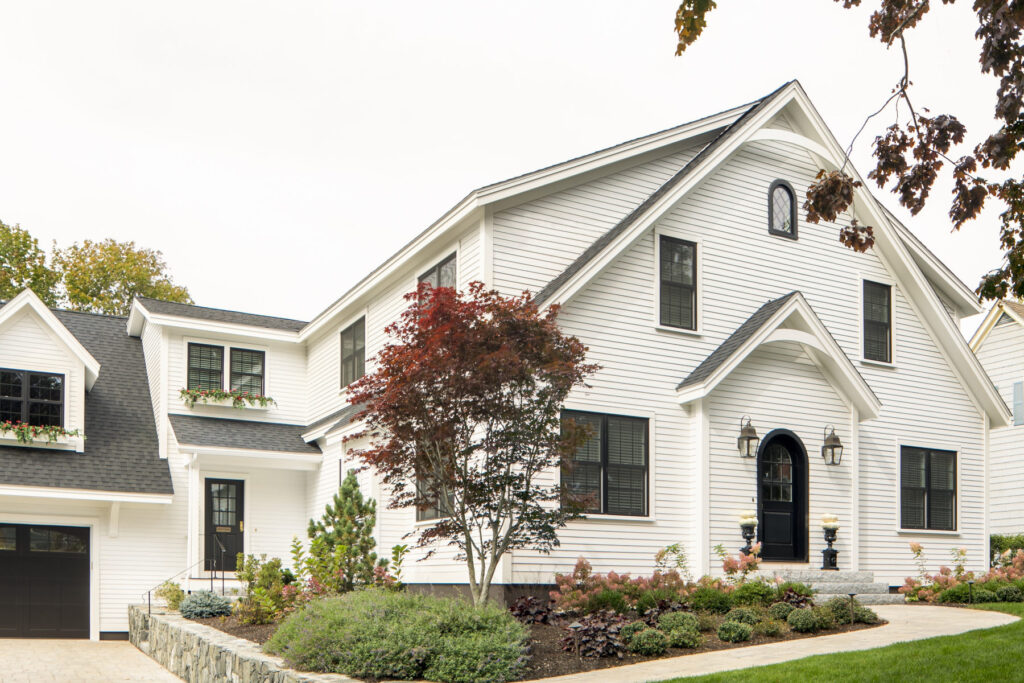 A white house featuring black trim, accompanied by a neatly paved driveway leading to the entrance.